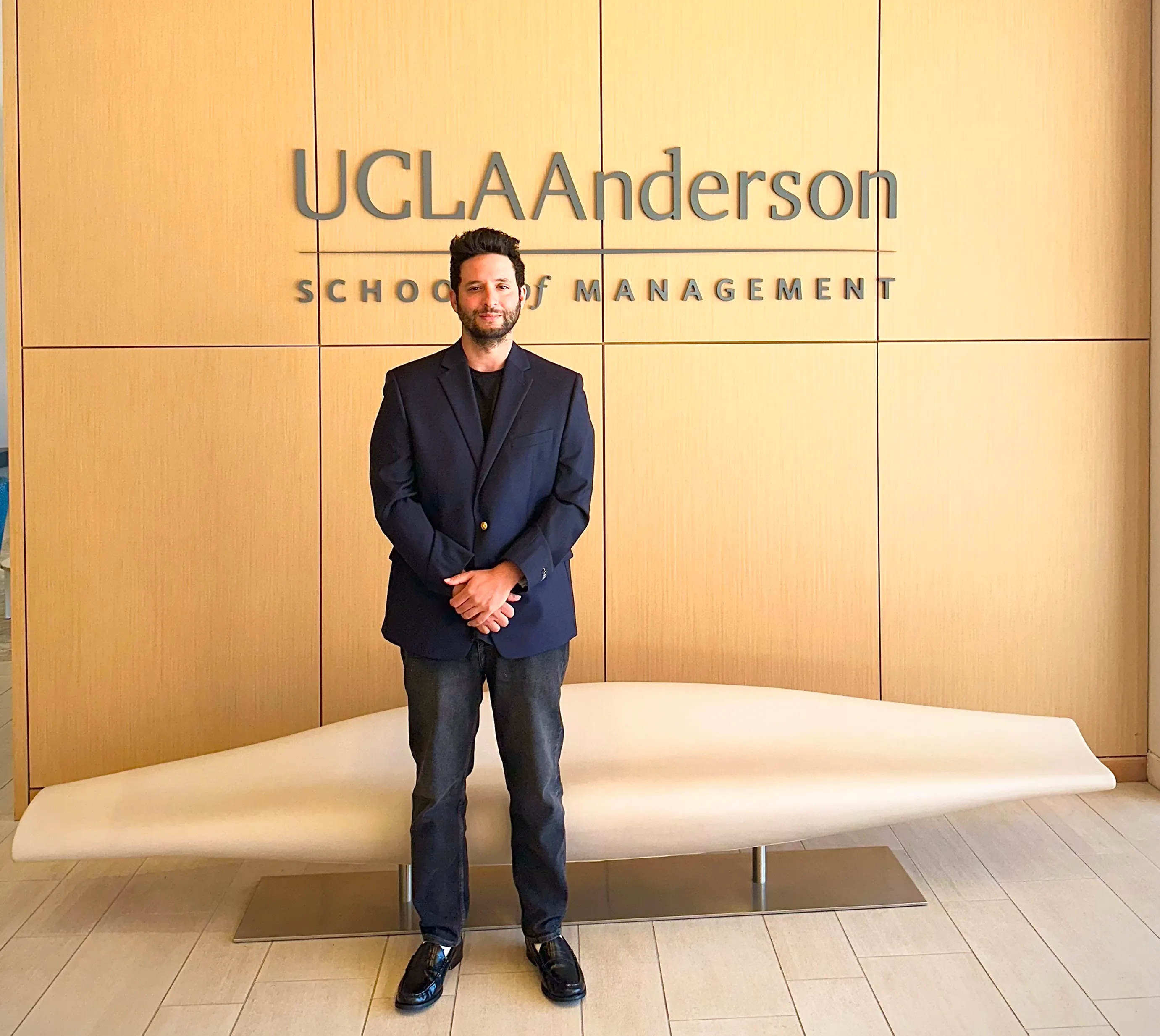 Alexander Bechelli standing in front of UCLA Anderson School of Management logo